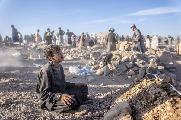 عزاداری یک پسر افغانستانی در کنار آرامگاه برادر کوچکش که بر اثر زلزله در ولسوالی زنده جان ولایت هرات در غرب افغانستان درگذشت. زمین لرزه مرگبار روز شنبه 9، 2023 هزاران کشته و زخمی بر جای گذاشت که تعداد بی شماری از خانه ها را در ولایت هرات با خاک یکسان کرد. (نگاره ازابراهیم نوروزی از خبرگزاری آسوشتیدپرس) - اسپوتنیک افغانستان  