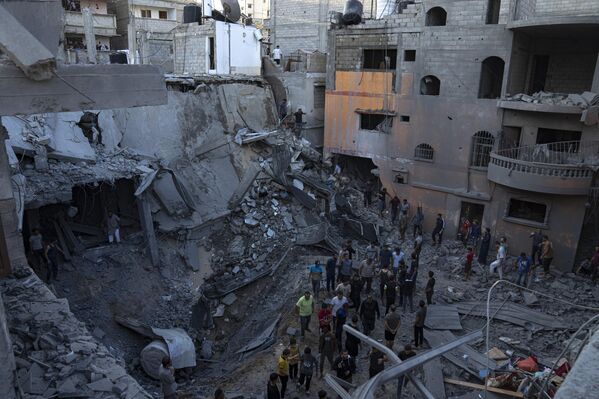 فلسطینیان در جستجوی بازماندگان در ساختمانی که در بمباران اسرائیل در خان یونس در نوار غزه ویران شده است. - اسپوتنیک افغانستان  