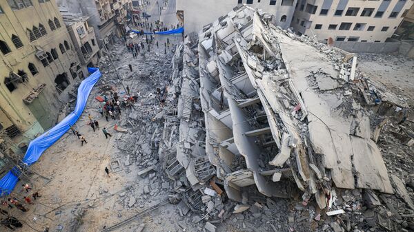 Люди осматривают руины здания, разрушенного в результате израильских ударов в городе Газа - اسپوتنیک افغانستان  