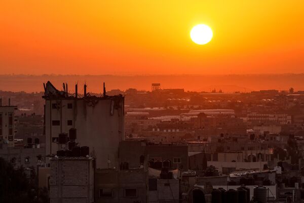 خورشید از پشت ساختمان مخروبه بر فراز خط افق خان یونس در جنوب نوار غزه طلوع می کند. - اسپوتنیک افغانستان  