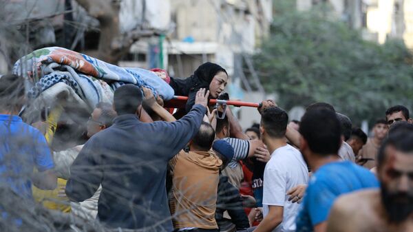Палестинцы эвакуируют раненую женщину после израильского удара по городу Газа - اسپوتنیک افغانستان  