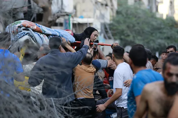 فلسطینیان در پی حمله ارتش اسرائیل به شهر غزه، یک زن زخمی را از بین آوار نجات دادند. - اسپوتنیک افغانستان  