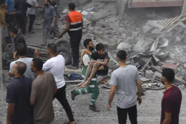 یکی از اعضای دفاع مدنی فلسطین پسری مجروح را حمل می کند که از زیر آوار خانه خانواده تاتاری که در حمله هوایی اسرائیل به شهر غزه ویران شده بود نجات یافت. - اسپوتنیک افغانستان  