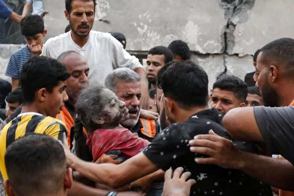 مردی یک دختر مجروح را از زیر آوار ساختمان فروریخته در پی حمله اسرائیل به شهر دیرالبلاح در مرکز نوار غزه بیرون آورد. - اسپوتنیک افغانستان  