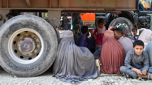 Афганские беженцы сидят под грузовиком по прибытии из Пакистана на афгано-пакистанской границе Торхам в провинции Нангархар - اسپوتنیک افغانستان  