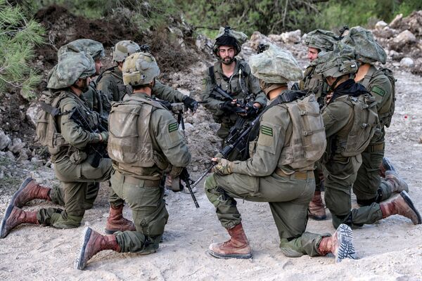 سربازان ارتش اسرائیل در 1 نوامبر 2023 در میان افزایش تنش‌های فرامرزی بین حزب‌الله و اسرائیل در حالی که درگیری‌ها در جنوب با شبه‌نظامیان حماس در نوار غزه ادامه دارد، زانو زده در موضعی در منطقه الجلیل بالا در شمال اسرائیل در نزدیکی مرز با لبنان نشسته‌اند. - اسپوتنیک افغانستان  