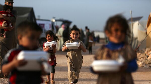Displaced Syrian children return to their tents with boxes of food distributed by a local charity organisation, before the 'Iftar' meal during the Muslim holy month of Ramadan, at a camp for displaced people on the outskirts of the rebel-held town of Dana, east of the Turkish-Syrian border in the northwestern Idlib province, on April 3, 2022. - اسپوتنیک افغانستان  