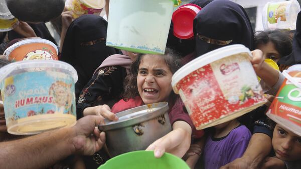 Палестинцы выстраиваются в очередь за едой во время продолжающейся израильской бомбардировки сектора Газа в Рафахе  - اسپوتنیک افغانستان  
