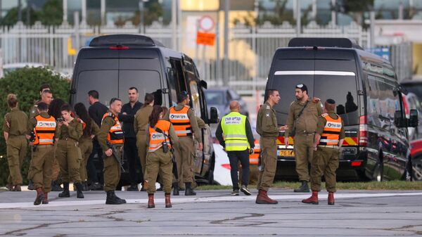 Израильские силы безопасности рядом с автобусами, ожидающими на вертолетной площадке медицинского центра Шнайдер в Тель-Авиве, на фоне подготовки к освобождению израильских заложников, удерживаемых Хамасом в секторе Газа - اسپوتنیک افغانستان  