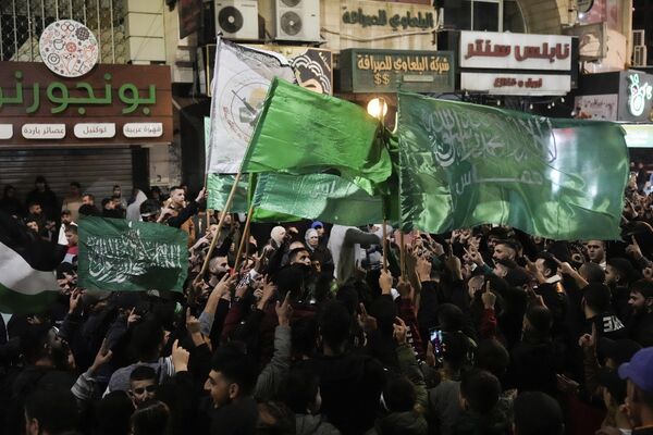 فلسطینی‌ها پرچم‌های حماس را در حالی که آزادی اسیران فلسطینی را در شهر نابلس کرانه باختری جشن می‌گیرند، به اهتزاز در می‌آورند، جمعه، 24 نومبر 2023. این آزادی در اولین روز از توافق آتش‌بس چهار روزه بین اسرائیل و حماس انجام شد. که شبه نظامیان غزه متعهد شده اند 50 گروگان را در ازای 150 فلسطینی اسیر اسرائیل آزاد کنند. (نگاره از ابومجدی محمد)  - اسپوتنیک افغانستان  