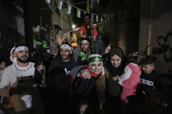 اسیل التیتی با سربند حماس، اسیر فلسطینی سابق که توسط مقامات اسرائیلی آزاد شده بود، در بلطا، اردوگاه آوارگان فلسطینی در نابلس، کرانه باختری، جمعه، 24 نومبر 2023، مورد استقبال دوستان و اعضای خانواده قرار گرفت. این آزادی در اولین روز از توافق آتش بس چهار روزه بین اسرائیل و حماس صورت گرفت که طی آن شبه نظامیان غزه متعهد شدند 50 گروگان را در ازای 150 فلسطینی زندانی توسط اسرائیل آزاد کنند. (نگاره از ابومجدی محمد) - اسپوتنیک افغانستان  