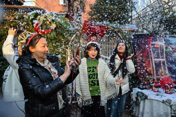 در 24 دسامبر 2023، مردم در باغ یک گل فروشی که در آن یک سمپاش فومی را که شبیه سازی برف در منطقه جینگ آن در شانگهای است، پرتاب می کند.  - اسپوتنیک افغانستان  