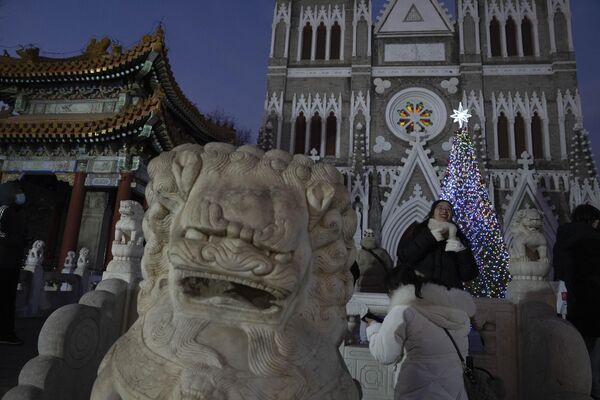 یکی از بازدیدکنندگان در روز کریسمس در پکن، دوشنبه، دسامبر، از نزدیکی تزئینات روشن خارج از کلیسای شیشیکو عکس می گیرد. 25، 2023. - اسپوتنیک افغانستان  