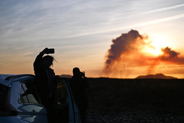فوران آتشفشانی در جنوب ایسلند در نزدیکی شهر گرینداویک. مردم از فوران گدازه ها و دود به هوابرخاسته عکس می گیرند. - اسپوتنیک افغانستان  
