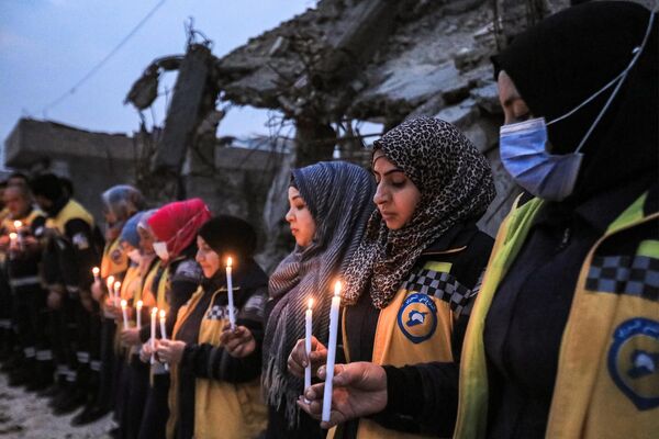 بازماندگان زلزله 6 فیبروری 2023 که شمال سوریه و ترکیه را ویران کرد، در مراسم یادبود با شمع های روشن در دست که توسط اعضای دفاع مدنی سوریه (کلاه سفیدها)، به مناسبت نخستین سالگرد فاجعه از سوی برخی از افراد سازماندهی شده است. - اسپوتنیک افغانستان  