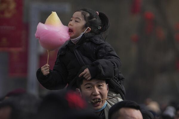 مردی هنگام بازدید از نمایشگاه معبد پارک لانگتان در دومین روز جشن سال نو قمری در پکن، یکشنبه، 11 فبروری 2024، فرزند خود را بر روی شانه خود حمل می کند. - اسپوتنیک افغانستان  