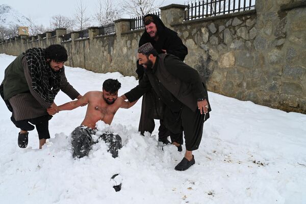 یک جوان افغان که در برف دفن شده است، در پی بارش برف در ولسوالی پغمان در حومه کابل در 19 فبروری 2024 قدرت خود را آزمایش می کند. - اسپوتنیک افغانستان  
