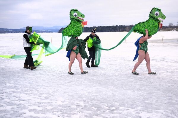 دو شناگر که لباس هیولای دریاچه ممفر را می‌پوشند، در مسابقه کلاه 25 متری در طول جشنواره شنای زمستانی در دریاچه یخ‌زده ممفرماگوگ، جمعه، فوریه، روی یخ راه می‌روند. 23، 2024، در نیوپورت، ورمونت - اسپوتنیک افغانستان  