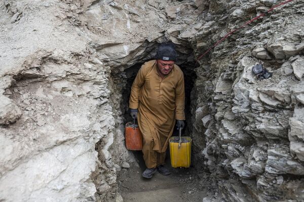 یک مرد افغانستانی سطل های پر از سنگ و خاک را از یک تونل در یک معدن طلا در کوه های یفتل پایین ولایت بدخشان را از دل کوه بیرون می آورد. - اسپوتنیک افغانستان  