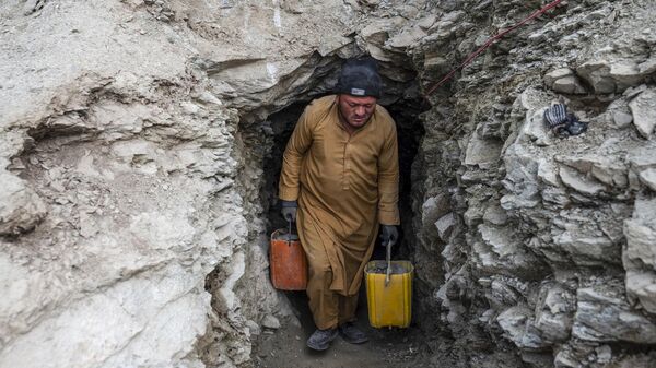 یک مرد افغان کانتینرهای پر از سنگ و خاک را از یک تونل در یک معدن طلا در کوه های یفتل سفلی ولایت بدخشان را از دل کوه بیرون می آورد - اسپوتنیک افغانستان  