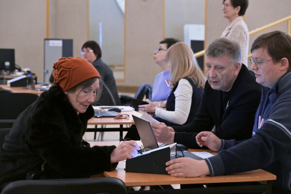 اعضای یک کمیسیون انتخابات حوزه ای از یک زن در انتخابات ریاست جمهوری روسیه در یکی از حوزه های رای گیری در مسکو ثبت نام کردند. - اسپوتنیک افغانستان  