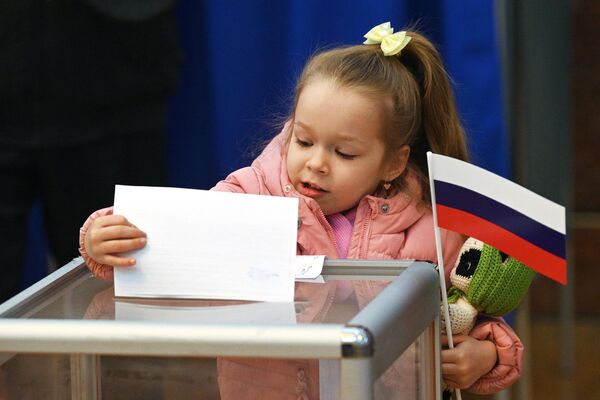 در جریان انتخابات ریاست جمهوری روسیه، یک دختر یک برگه رای را در صندوق رای در یک شعبه رای در سفارت روسیه در مینسک می گذارد. - اسپوتنیک افغانستان  