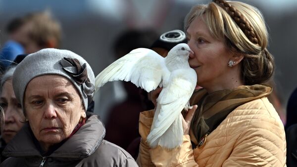 زنی کبوتر سفیدی را در مراسم ترحیم قربانیان حمله تروریستی به تالار کنسرت کروکوس سیتی در دست دارد - اسپوتنیک افغانستان  
