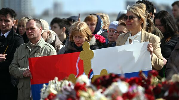 Люди с плакатом в цветах российского и сербского флагов у стихийного мемориала в память о жертвах теракта в Крокус Сити Холле. - اسپوتنیک افغانستان  