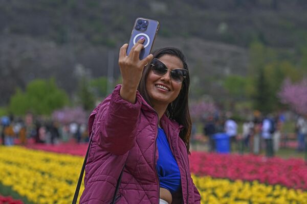 یک گردشگر با گوشی همراه در باغ لاله یادبود ایندیرا گاندی در سرینگار در 3 اپریل 2024 سلفی می گیرد. - اسپوتنیک افغانستان  