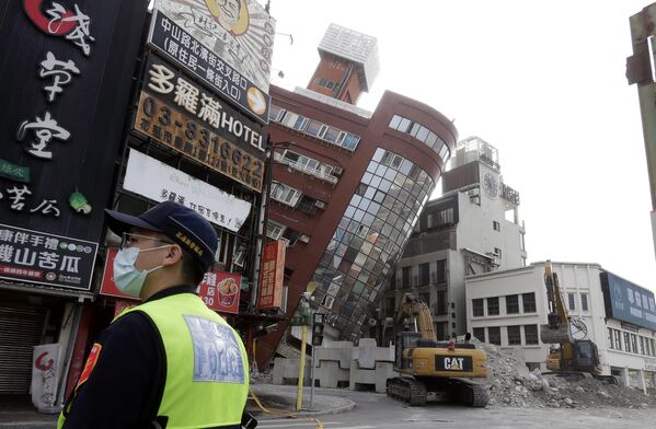 نگاه پولیس به یک ساختمان نیمه فروریخته یک روز پس از زلزله قدرتمندی که در شهر Hualien، شرق تایوان، پنجشنبه، 4 اپریل 2024 رخ داد، در زاویه عنوان ایستاده است. - اسپوتنیک افغانستان  