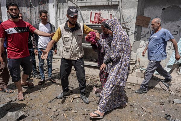 پس از حمله اسرائیل به اردوگاه البریج در مرکز نوار غزه در 22 اپریل 2024، در بحبوحه نبردهای جاری بین اسرائیل و گروه شبه نظامی حماس، یک زن فلسطینی زخمی قبل از انتقال به شفاخانه به آمبولانس اسکورت می شود. (عکس از خبرگزاری فرانسه) - اسپوتنیک افغانستان  