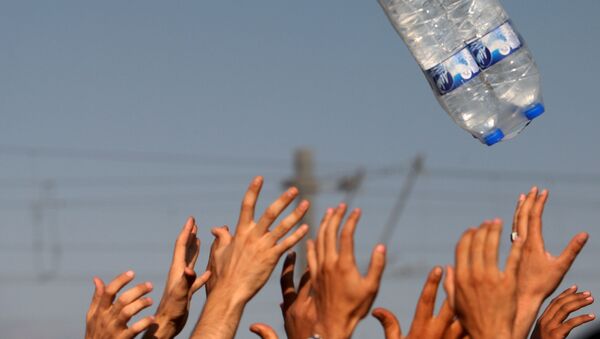 Мигранты ловят воду, брошенную им волонтерами гуманитарных организаций на греческо-македонской границе - اسپوتنیک افغانستان  