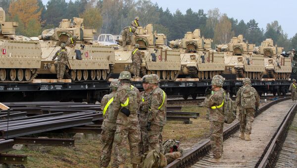 Members of the US Army 1st Brigade, 1st Cavalry Division, unload heavy combat equipment including Bradley Fighting Vehicles at the railway station near the Rukla military base in Lithuania, on October 4, 2014 - اسپوتنیک افغانستان  