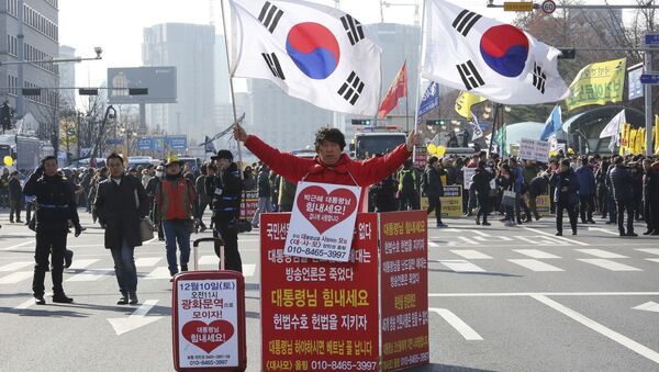 Мужчина держит национальные флаги Южной Кореи в поддержку президента Пак Кын Хе - اسپوتنیک افغانستان  