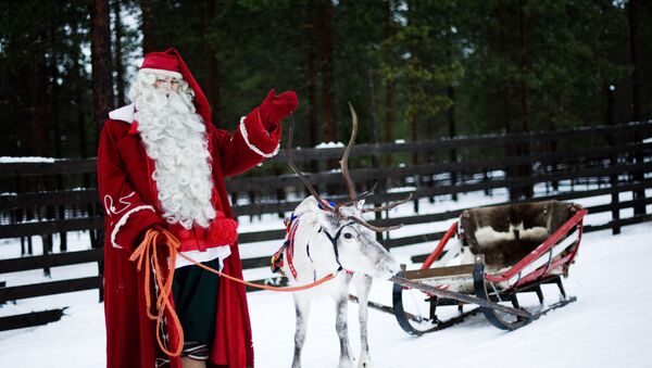 Santa Claus waves as he stands with a reindeer and sled outside Rovaniemi, Finnish Lapland on December 15, 2011 - اسپوتنیک افغانستان  