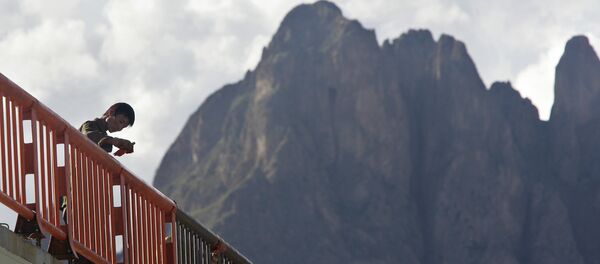 A worker, dwarfed by surrounding mountains, paints the railing on the Lhasa River Bridge, on the outskirts of Lhasa - اسپوتنیک افغانستان  