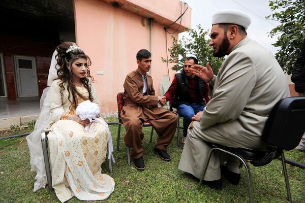 عروس و داماد عراقی در حال گوش‌دادن به یک روحانی در پایگاه پناهجویان - اسپوتنیک افغانستان  
