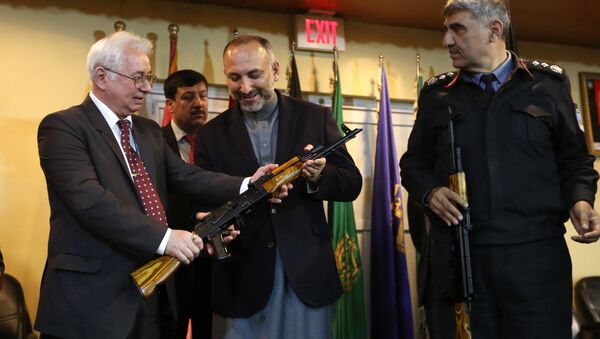 Russian Federation Ambassador, Alexander Mantytskiy, left, hands over an AK-47 to Afghan National Security Advisor, Mohammad Hanif Atmar, center, as the symbol of his country's military donation to the Afghan government, at Kabul International Airport, Wednesday, Feb. 24, 2016. - اسپوتنیک افغانستان  