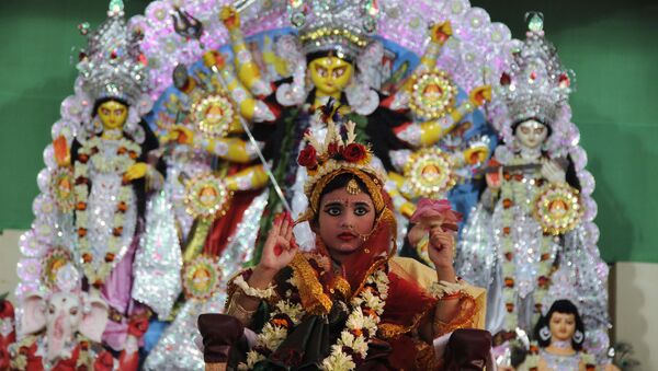A young Indian Hindu unmarried girl, Nilanjana Chakraborty (5), known as a 'kumari' and dressed as the Hindu goddess Durga, puts her hand up during a ritual for the Durga Puja festival at Ramakrishna Mission in Agartala, the capital of northeastern state of Tripura on October 21, 2015 - اسپوتنیک افغانستان  