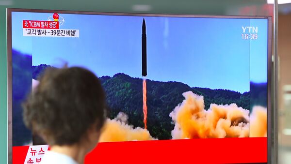 A woman walks past a television screen showing a picture of North Korea's launch of an intercontinental ballistic missile (ICBM), at a railway station in Seoul on July 4, 2017. - اسپوتنیک افغانستان  