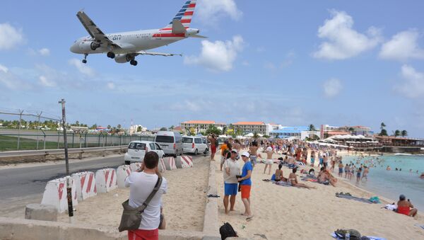 A plane lands at the Princess Juliana International Airport as beachgoers watch in Philipsburg, St. Maarten, a Dutch Caribbean territory, Thursday, July 13, 2017. On Wednesday, a New Zealand tourist was killed by the blast from a jetliner taking off when she was knocked into a wall as she tried to cling to a fence to feel the blast. - اسپوتنیک افغانستان  