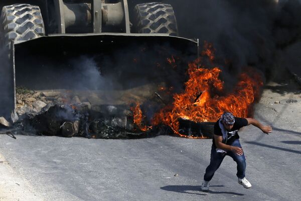یک معترض فلسطینی به دور  بولدوزر ارتش اسرائیل در جریان درگیری در روستای  در غرب رام الله - اسپوتنیک افغانستان  