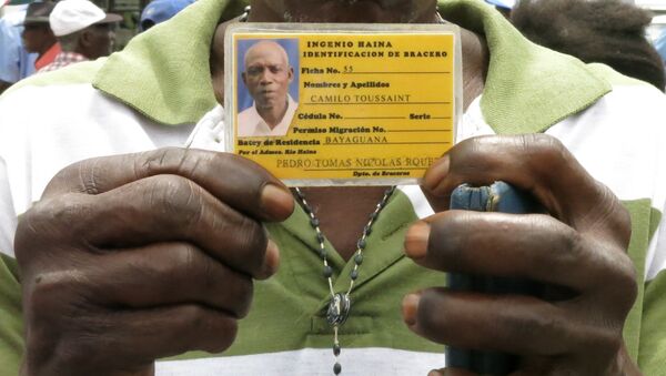 Former sugar cane worker Camilo Toussaint shows his identification card from the company he worked for during a sit-in outside Haiti's embassy in Santo Domingo - اسپوتنیک افغانستان  