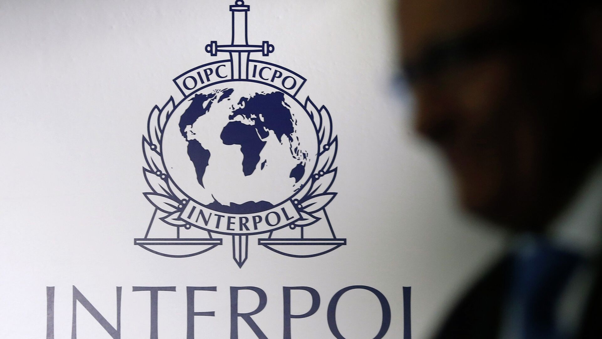 A man passes an Interpol logo during the handing over ceremony of the new premises for Interpol's Global Complex for Innovation, a research and development facility, in Singapore September 30, 2014 - اسپوتنیک افغانستان  , 1920, 11.05.2022