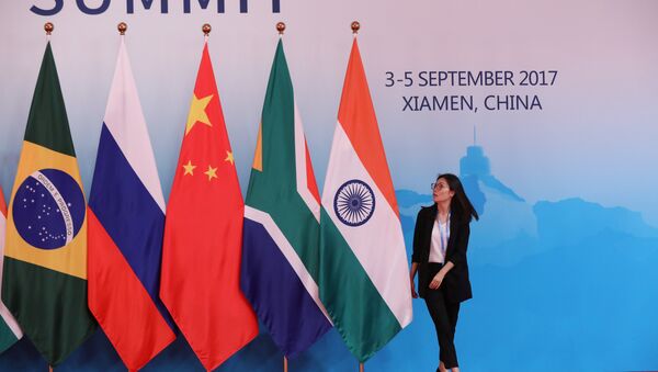 A staff worker walks past the national flags of Brazil, Russia, China, South Africa and India before a group photo during the BRICS Summit at the Xiamen International Conference and Exhibition Center in Xiamen, southeastern China's Fujian Province, China September 4, 2017 - اسپوتنیک افغانستان  