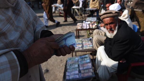 In this photograph taken on December 29, 2014, an Afghan customer (L) counts his Afghani currency notes at a currency exchange market along the roadside in Kabul - اسپوتنیک افغانستان  