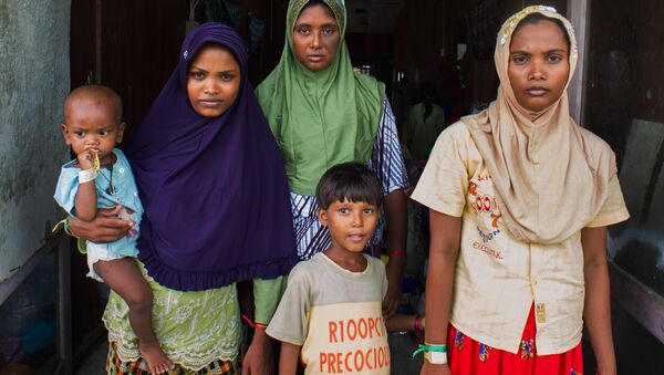 In this photograph taken on May 28, 2015, Rohingya migrant women from Myanmar (L-R) Rubuza Hatu, 21, Rehana Begom, 24 and Rozama Hatu, 23, stand at a confinement camp at Bayeun district in Indonesia's Aceh province after Indonesian fishermen rescued about 400 Rohingya migrants from Myanmar and Bangladesh from a boat on May 20, 2015 off the eastern coast of Aceh. - اسپوتنیک افغانستان  
