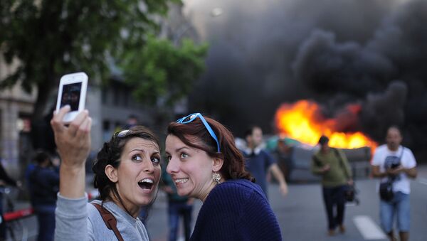 Селфи двух женщин на фоне горящего мусорного контейнера во время митинга в Барселоне - اسپوتنیک افغانستان  