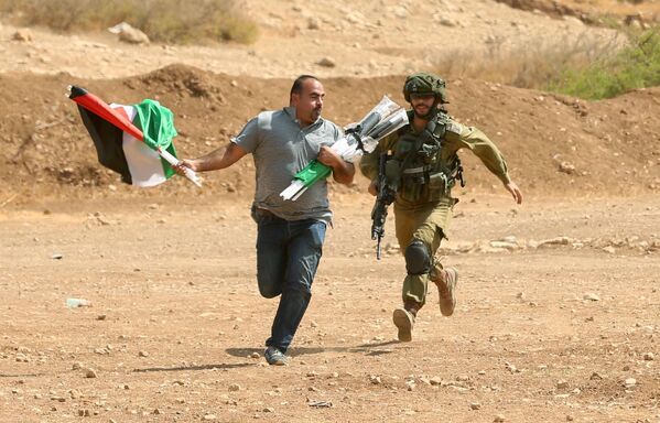 یک سرباز اسرائیلی پس از یک درگیری در فلسطین در کرانه باختری در نزدیکی شهر توبس در حال دستگیری مرد فلسطینی - اسپوتنیک افغانستان  