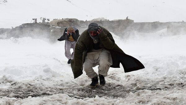 Afghan survivors of an avalanche run to get relief goods distributed by an Afghan army helicopter in the Paryan district of Panjshir province, north of Kabul on March 1, 2015 - اسپوتنیک افغانستان  